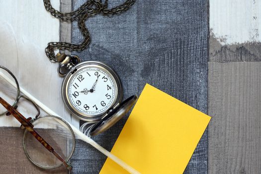 Vintage still life with old spectacles near feather and pocket watch