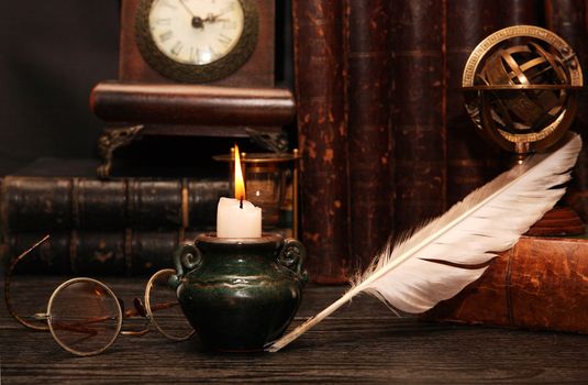 Vintage still life. Various old things and books near lighting candle