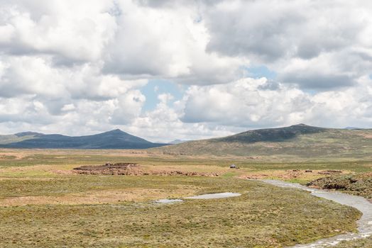 A farm landscape at the foot of the Black Mountain Pass. A river, stone huts and sheep are visible