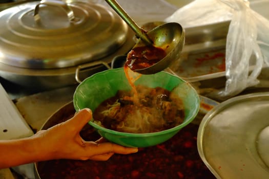 A spicy soup ladle in a cup, a spicy soup in northern Thailand.Northern Thai food made of rice vermicelli or rice noodle in spicy sauce with pork or meat.