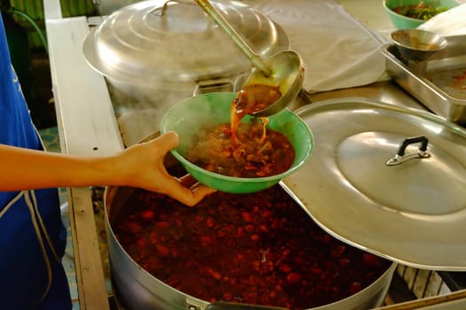 A spicy pork sauce ladle in a cup, a spicy soup in northern Thailand.Northern Thai food made of rice vermicelli or rice noodle in spicy sauce with pork or meat.