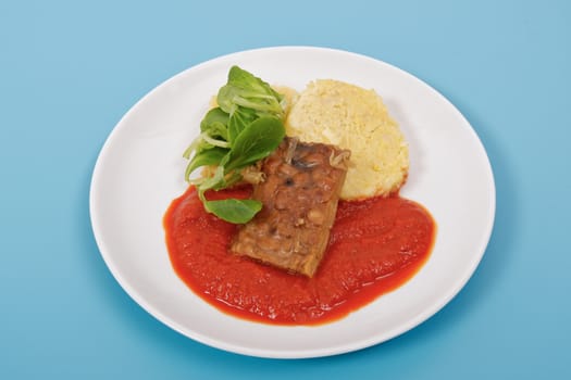 Tempeh with tomato sauce and dumplings on a blue background