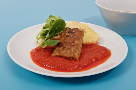 Tempeh with tomato sauce and dumplings on a blue background