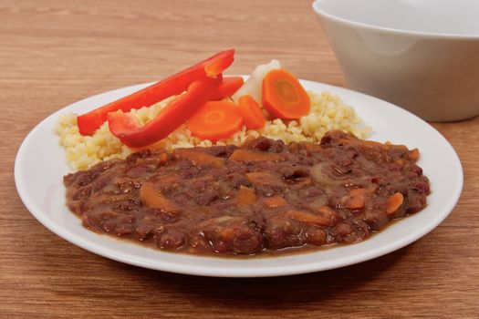 Azuki with vegetables on steam and bulgur on a wooden table