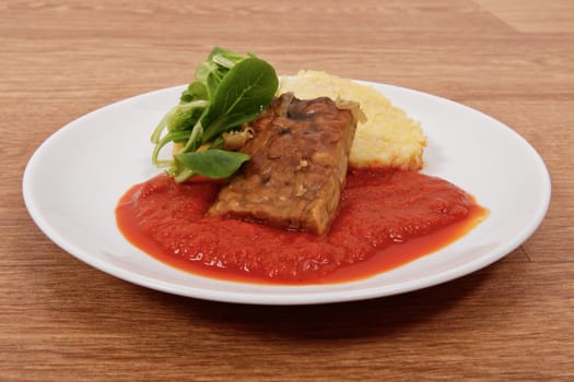 Tempeh with tomato sauce and dumplings on a wooden table