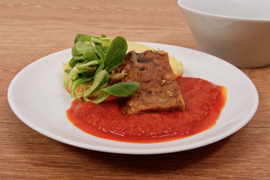 Tempeh with tomato sauce and dumplings on a wooden table