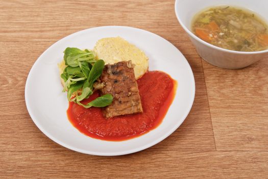 Tempeh with tomato sauce and dumplings on a wooden table