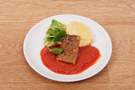 Tempeh with tomato sauce and dumplings on a wooden table