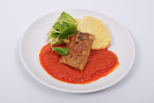 Tempeh with tomato sauce and dumplings on a white background