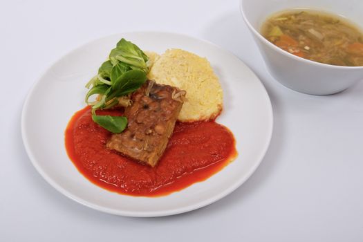 Tempeh with tomato sauce and dumplings on a white background