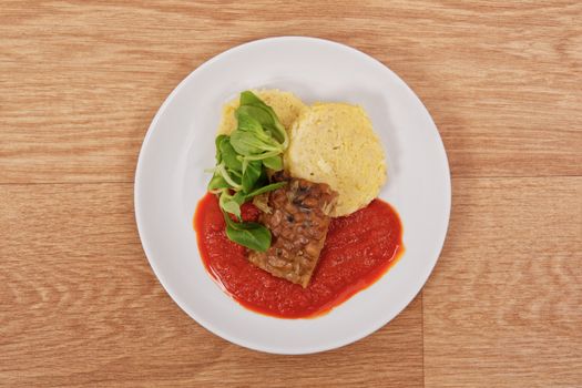 Tempeh with tomato sauce and dumplings on a wooden table