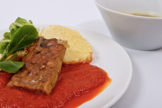 Tempeh with tomato sauce and dumplings on a white background