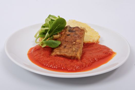 Tempeh with tomato sauce and dumplings on a white background