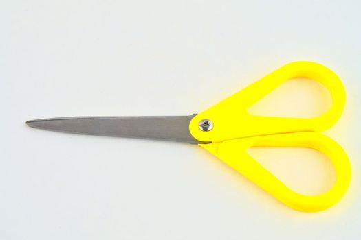 Yellow scissors isolated on a white background. Top view.