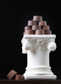 Stack of Fine Artisan Chocolates Stacked On White Pillar Column.