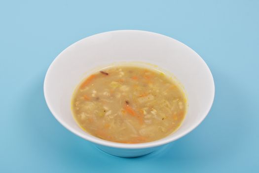Soup with pasta and vegetables on a blue background