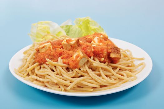 Bolognese spaghetti with tofu on a blue background