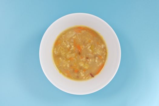 Soup with pasta and vegetables on a blue background