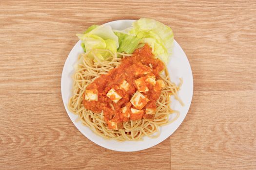 Bolognese spaghetti with tofu on a wooden table