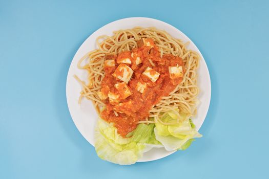 Bolognese spaghetti with tofu on a blue background