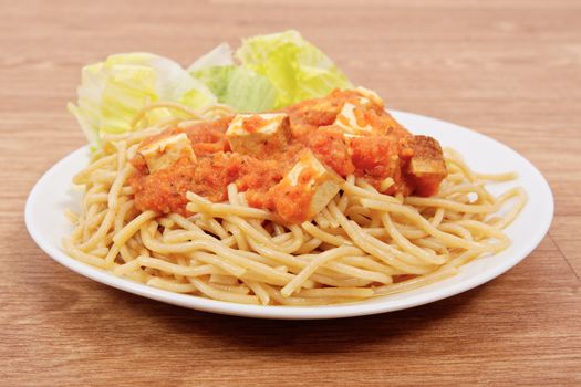 Bolognese spaghetti with tofu on a wooden table