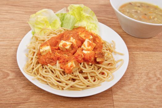 Bolognese spaghetti with tofu on a wooden table