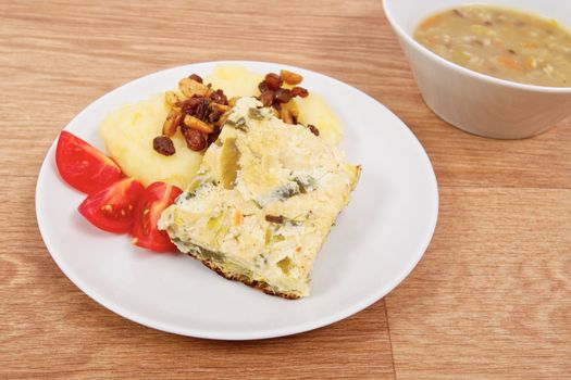Baked leek with mashed potatoes on a wooden table