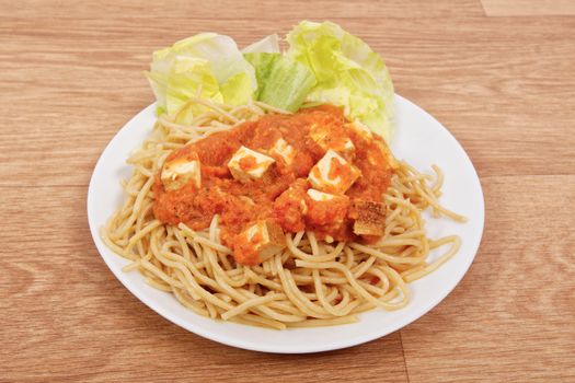 Bolognese spaghetti with tofu on a wooden table