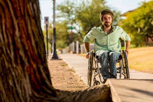 Man in a wheelchair looking over sidewalk obstacle