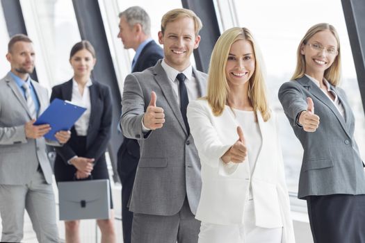 Successful young business people showing thumbs up sign