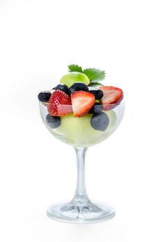 Fresh forest berries and melon in a glass on a white background