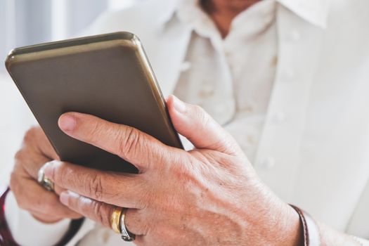 close up image of Senior woman using her mobile phone background.  An idea of modern lifestyle, communication,telecommunication,connectivity, social networking