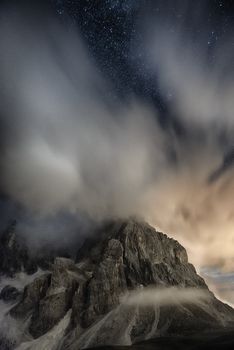 Cimon della Pala in the night with clouds and stars