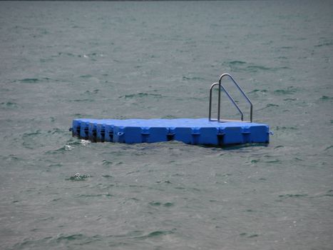 Isolated Blue Ponton Swimming Platform on Stormy Cold Water