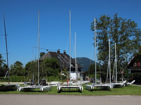 White Catamarans Sailboats Ashore on Grass Field in Summer