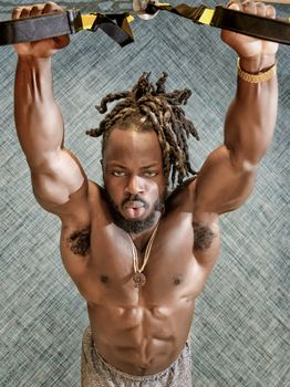 Handsome, young, muscular African American man, a bodybuilder, exercising in the gym.