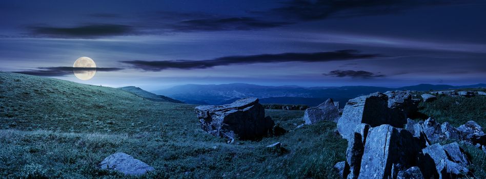 beautiful panorama of Runa mountain at night in full moon light. huge rocky formation on the hillside and peak in the distance. wonderful landscape of Carpathians