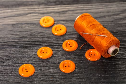 spool of threads and buttons on a wooden background