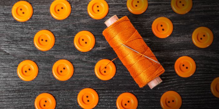 spool of threads and buttons on a wooden background