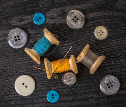 spool of threads and buttons on a wooden background