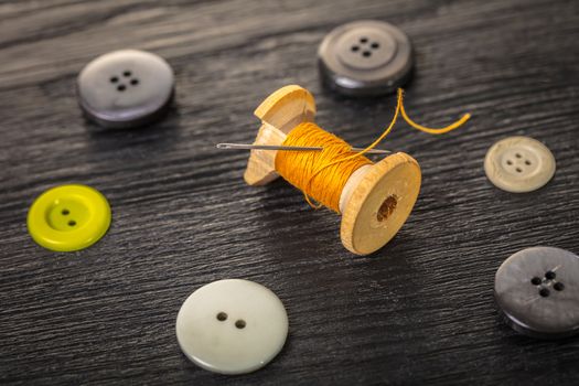 spool of threads and buttons on a wooden background