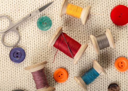 colorful threads and buttons on white knitted fabric