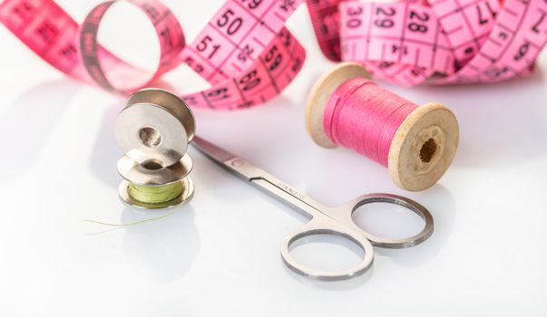 spool of pink thread and meter on white background