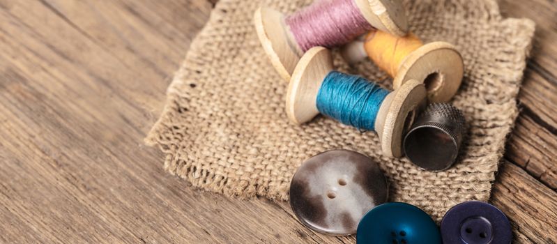 spool of threads and buttons on a wooden background