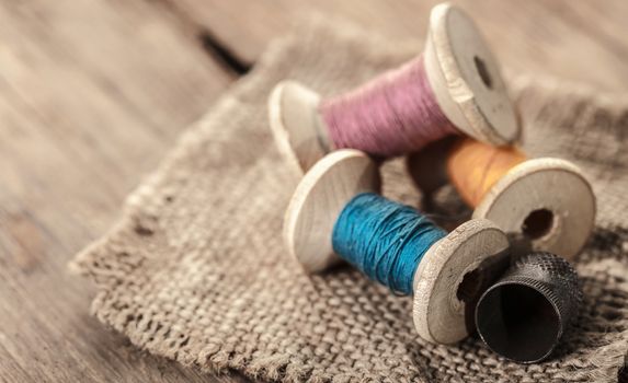 spool of threads and thimble on a wooden background