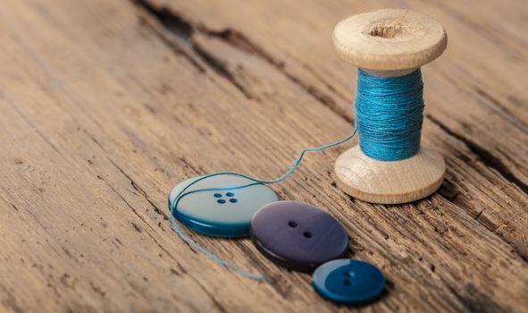 spool of threads and buttons on a wooden background