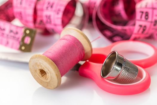 spool of pink thread and meter on white background