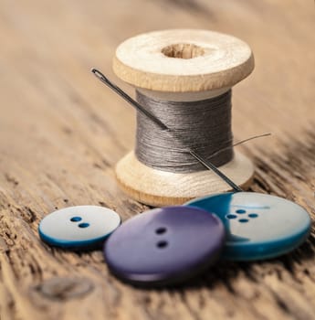 spool of threads and buttons on a wooden background