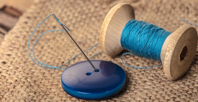 blue button with needle and thread close-up