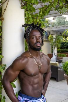 Handsome young muscular African American man posing shirtless outside.